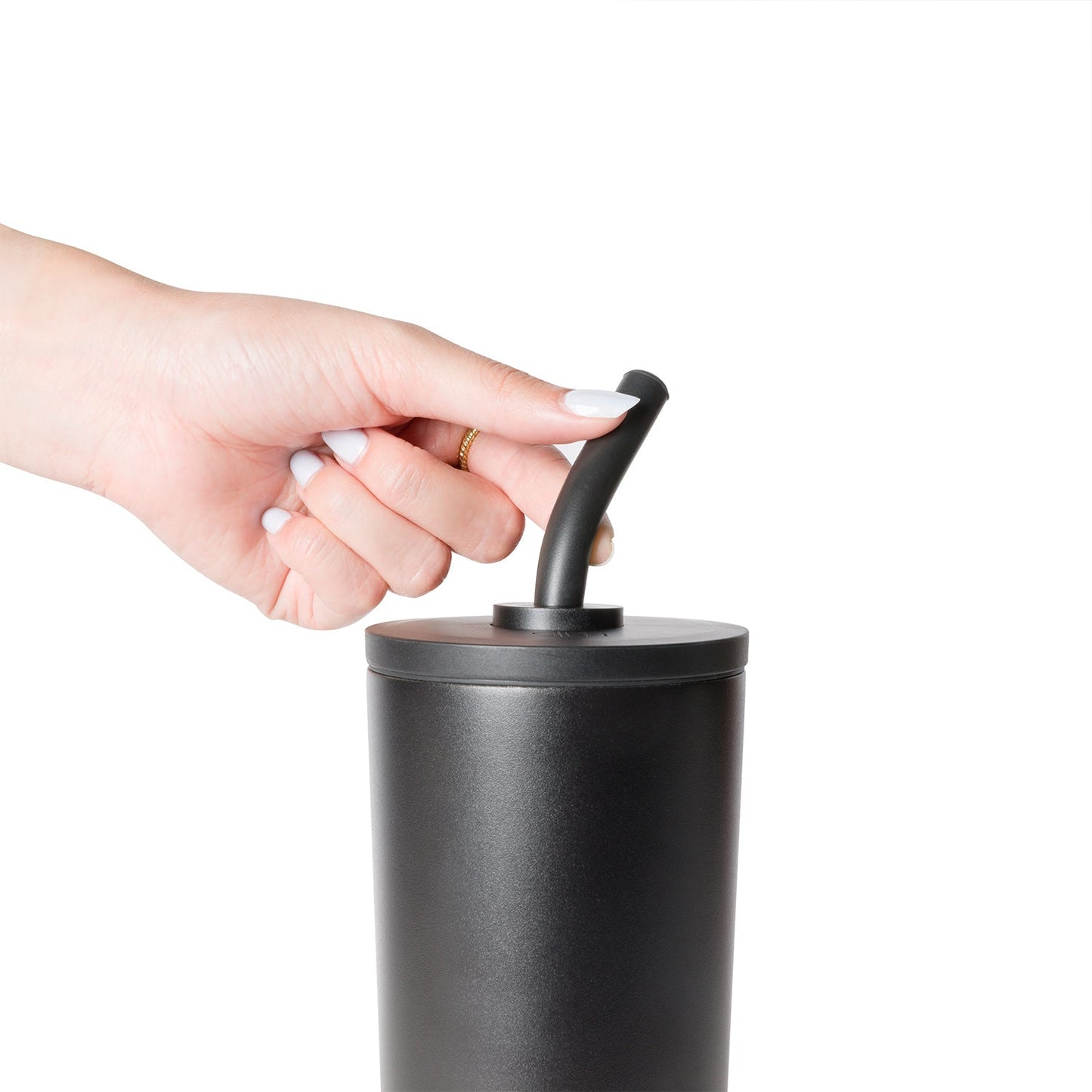 Woman's hand with white nail polish and gold ring holding a Simple Modern drinkware product with black straw and lid assembly