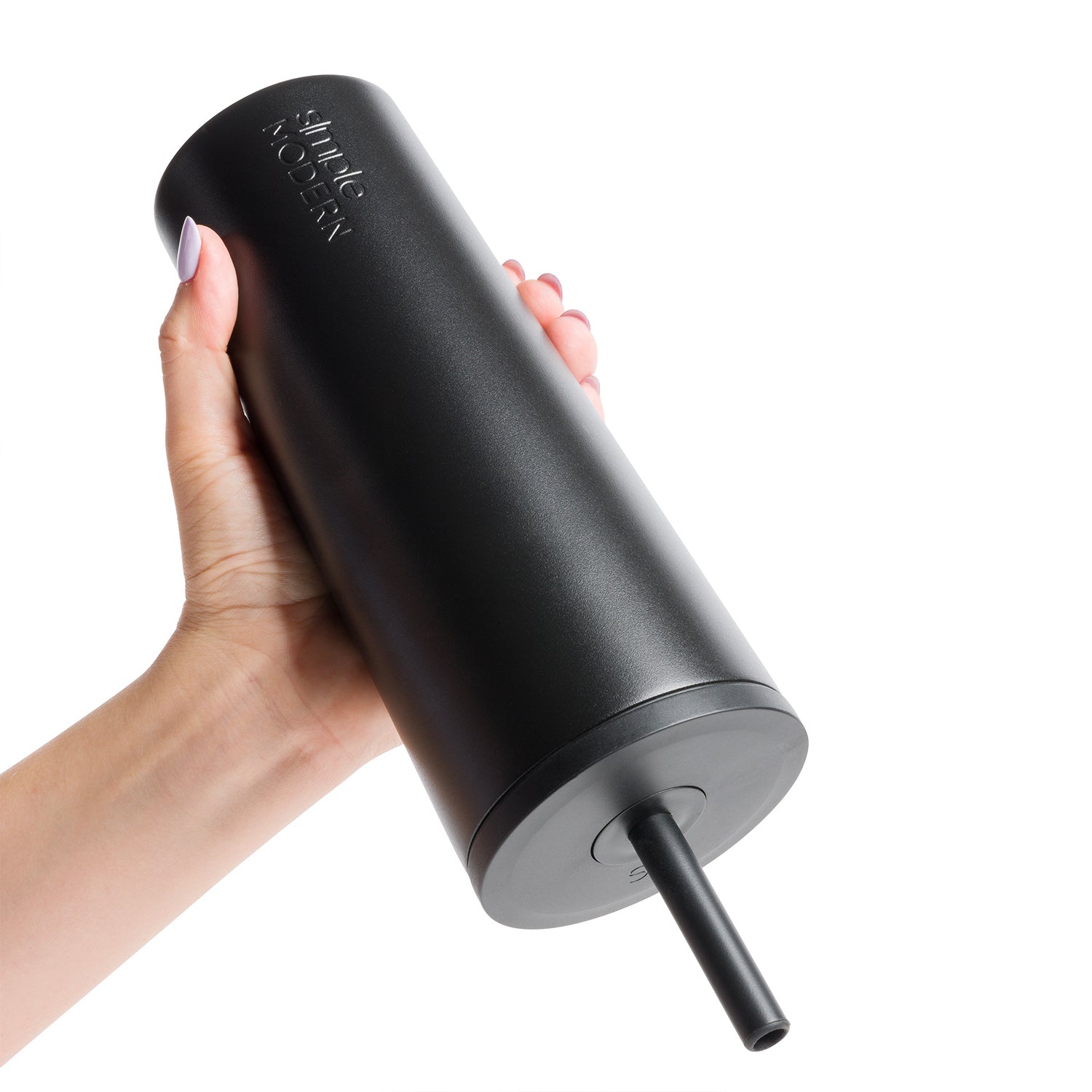 Hand holding a matte black tumbler with gray base, displayed against a white background